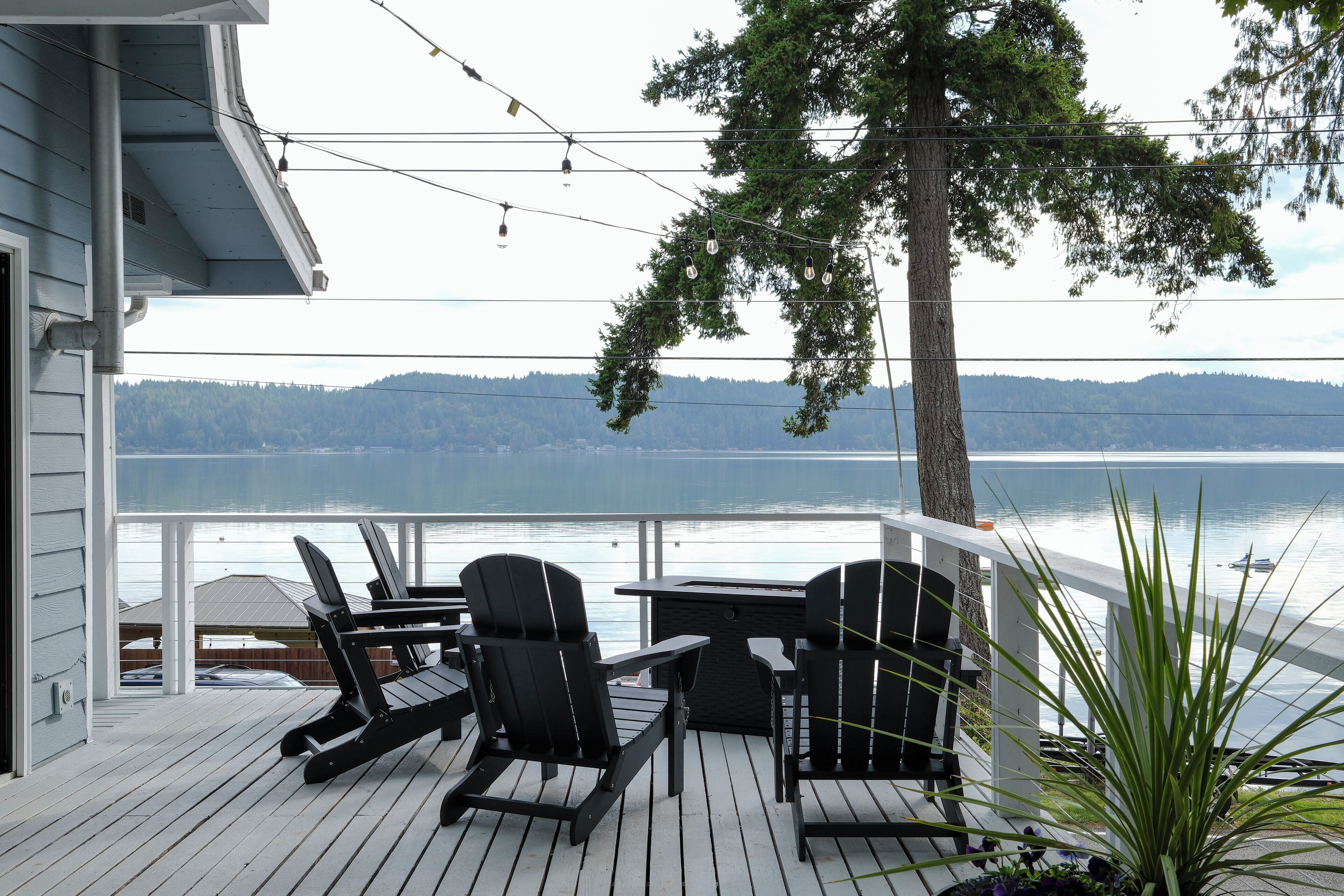 A deck with outdoor seating, overlooking a lake and hills.