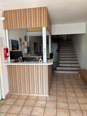 A reception desk with a wooden panel design, a clock, and a Wi-Fi sign. - Hôtel du Rocher (Le Caylar)