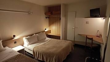 A hotel room with two single beds, a desk, a chair, and a television on a shelf.