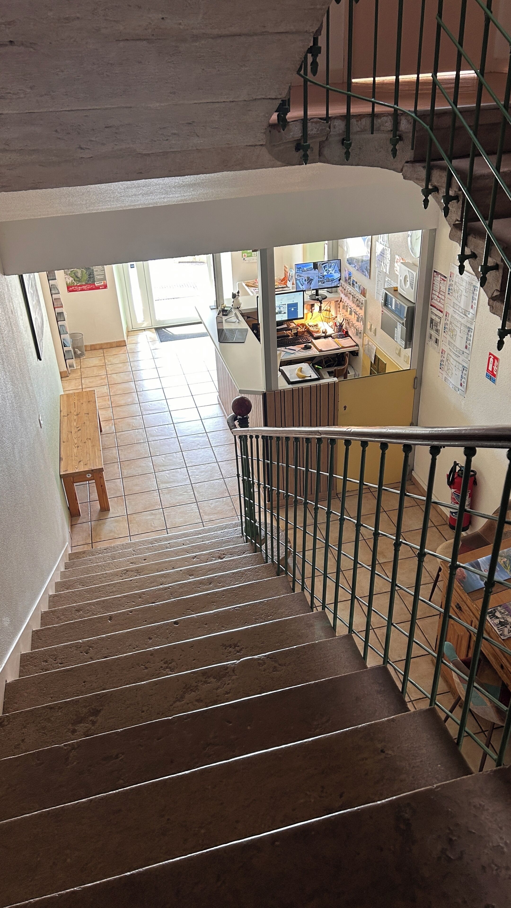 Una escalera con barandas metálicas que conduce a una habitación con un escritorio, monitores de computadora y un extintor.