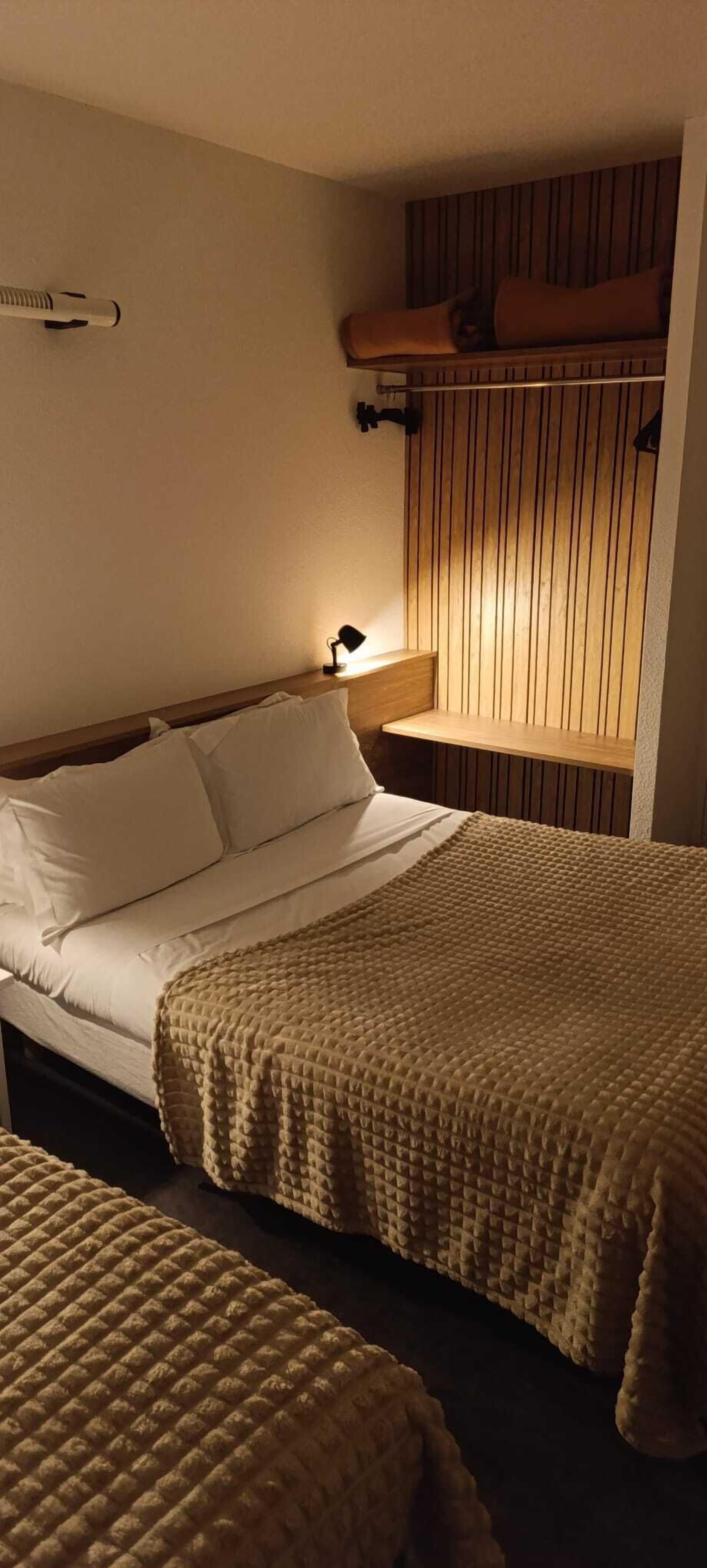 Une chambre d’hôtel avec un lit, une table de chevet avec une lampe et un mur recouvert de panneaux de bois.