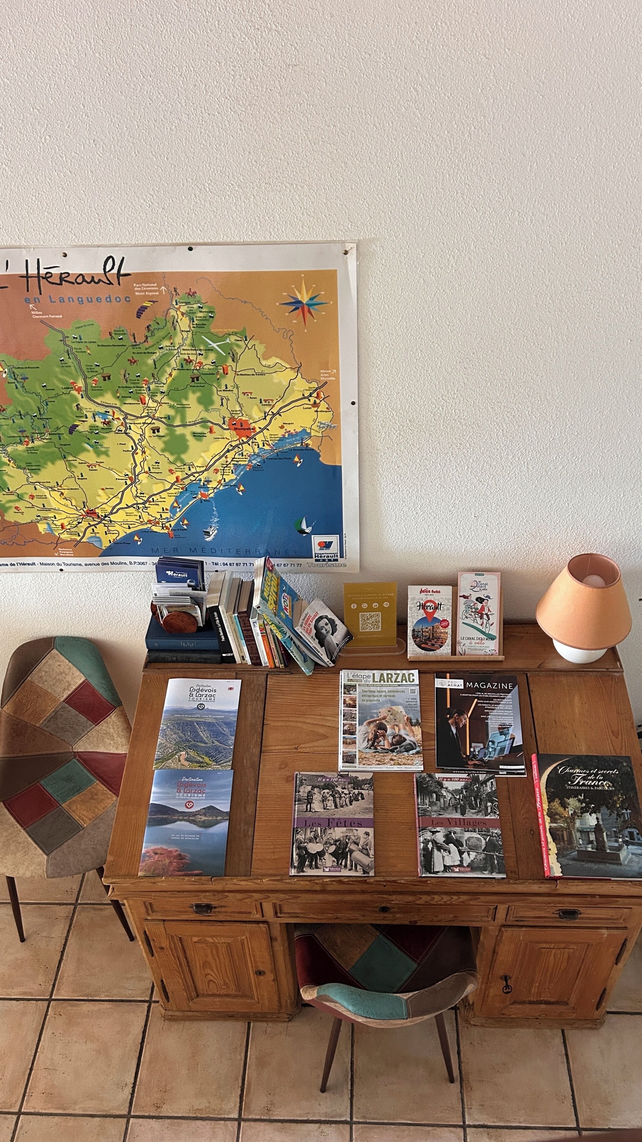 A wooden desk with a map, books, and a lamp.