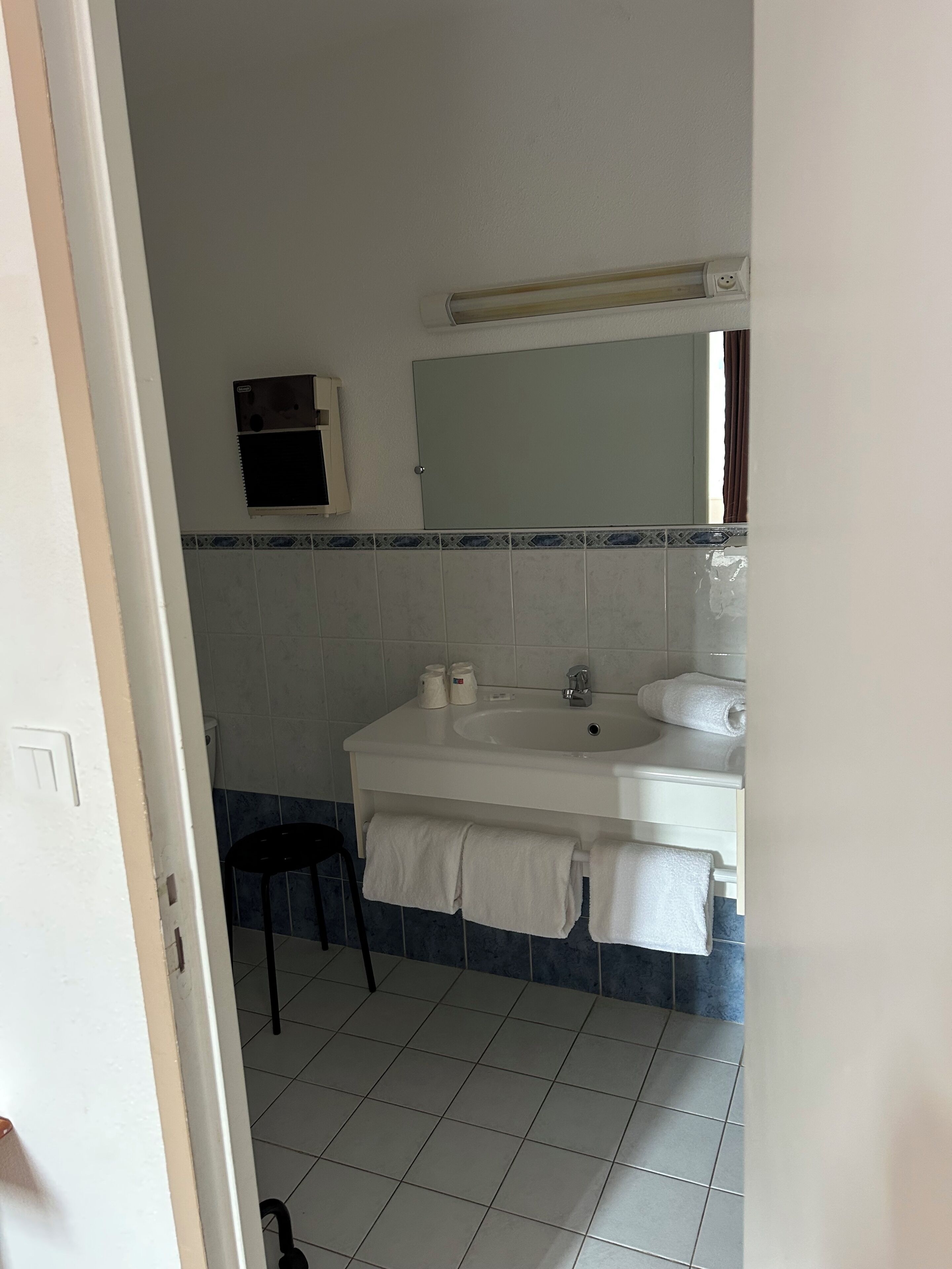 A bathroom with a white sink, mirror, and tiled floor.