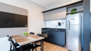 Eine moderne Küche mit Einbauofen, Kühlschrank und Spüle. Ein Esstisch mit Stühlen und einer kleinen Pflanze steht daneben.