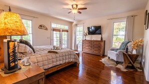 A spacious bedroom with a large bed, wooden dresser, and a ceiling fan. - The Retreat at Paradise Hills  (Dandridge)