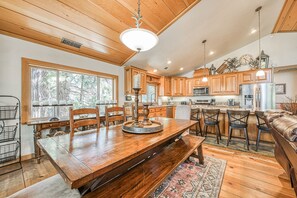 A spacious kitchen with wooden cabinets, a dining table with chairs, and a bar area with stools.