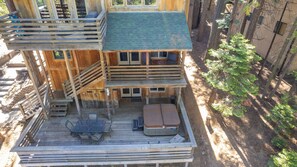A multi-level wooden cabin with a deck, outdoor seating, and a staircase.