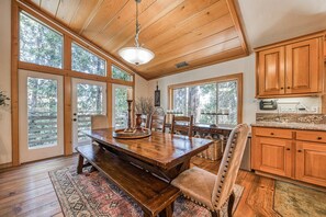 A spacious dining area with a wooden table, chairs, and a chandelier.