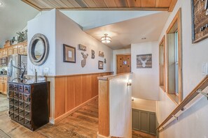 A hallway with wooden paneling, a refrigerator, a sink, and a staircase.