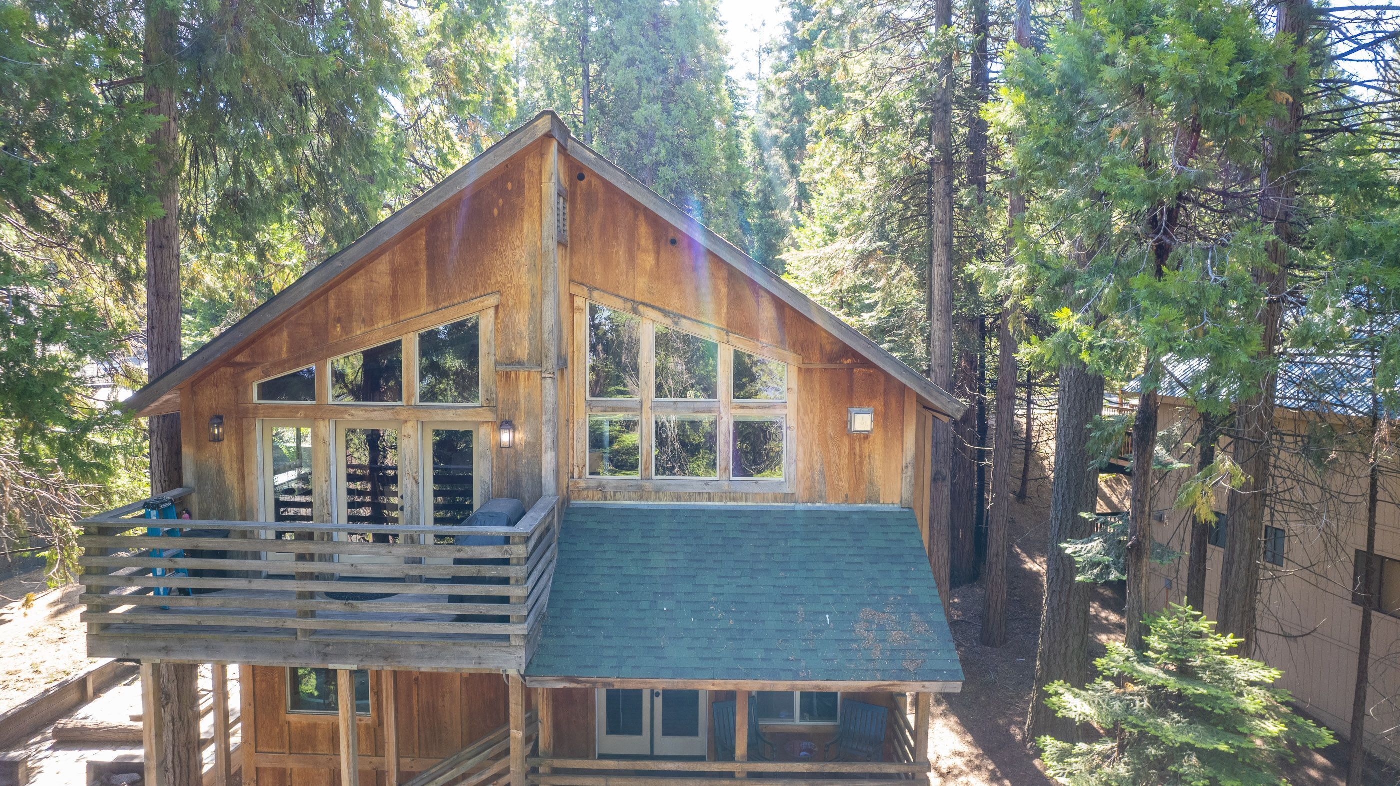A wooden cabin with a balcony, large windows, and a steep roof.