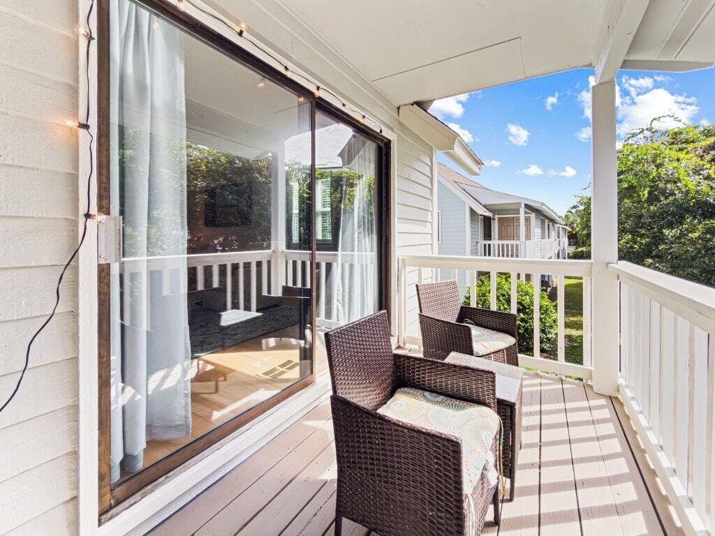 A covered porch with wicker furniture and a sliding glass door.