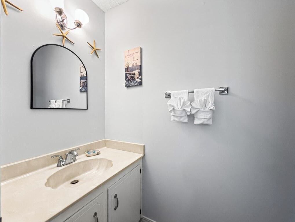 A bathroom with a sink, mirror, towel rack, and decorative starfish.