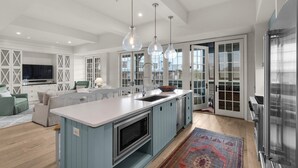 A modern kitchen with a large island, pendant lights, and a view to the outside. - Charming Coastal Escape – Private Beach & Pool Access In Rosemary Beach (Rosemary Beach)
