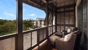 A balcony with wicker furniture and a view of buildings and trees. - Charming Coastal Escape – Private Beach & Pool Access In Rosemary Beach (Rosemary Beach)