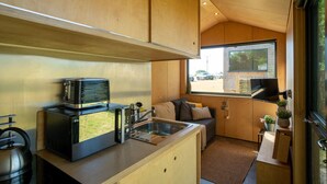 A compact kitchen with a stove, sink, and a small seating area with a window.
