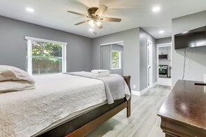 Quarto com cama, ventilador de teto, televisão e vista para o exterior.