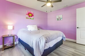 A bedroom with a bed, a nightstand, a lamp, and a ceiling fan.