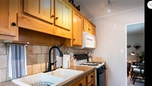 A kitchen with wooden cabinets, a white microwave, a gas stove, and a sink.