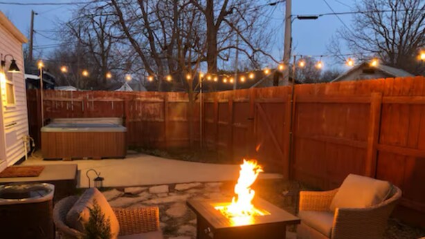 A backyard with a fire pit, outdoor furniture, and a wooden fence.