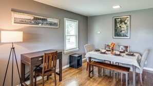 Un coin repas avec une table en bois dressée pour quatre personnes, un banc et un lampadaire sur trépied.