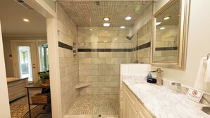 Ein modernes Badezimmer mit bodengleicher Dusche, einem Waschtisch mit Marmorplatte und einem großen Spiegel.