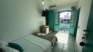 A small, clean room with a bed, a desk, and a window with a view of the outside. - Pousada Real Paraty (Paraty)