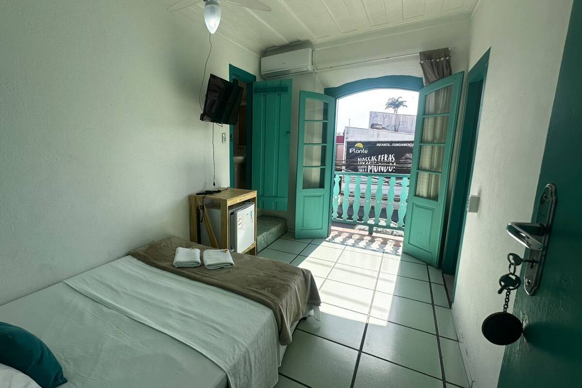 Una habitación pequeña y limpia con cama, escritorio y ventana con vista al exterior.