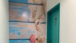 A hallway with a wall painted to resemble a beach scene, including a starfish and seashells. - Pousada Real Paraty (Paraty)