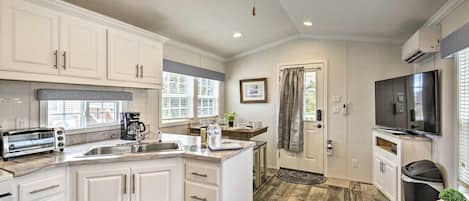 A compact kitchen with white cabinetry, a built-in toaster, and a ceiling fan.