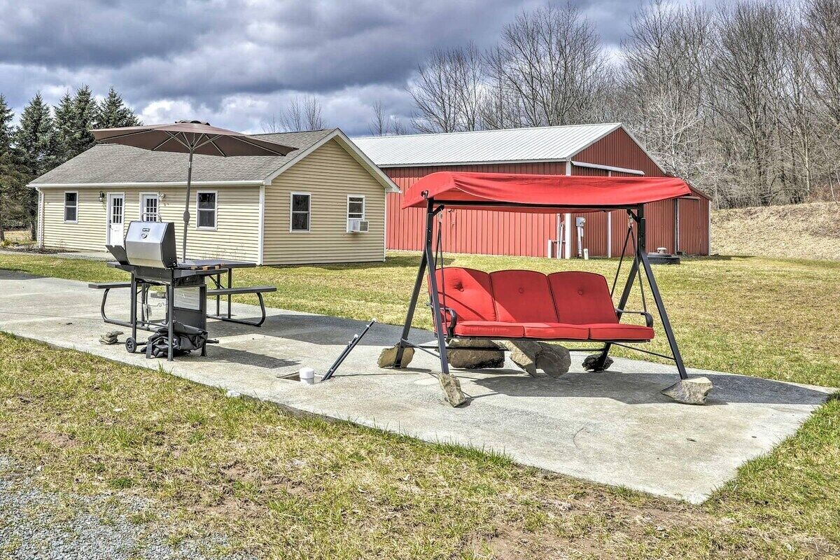 Un espace extérieur aménagé avec un barbecue, une balançoire et une table de pique-nique.