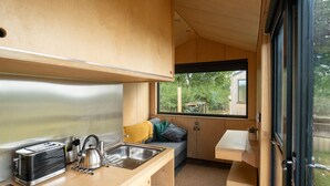 A compact kitchen with a sink, stove, and a window overlooking greenery. - Cosy Cabin at The Coppleridge 2 (Motcombe)