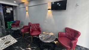 A modern lounge area with red upholstered chairs, a flat-screen TV mounted on the wall, and a marble floor. - Old City Kadıköy Otel (Istanbul)