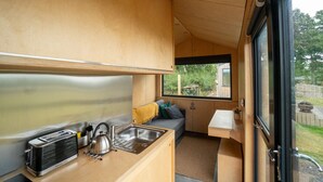 A compact kitchenette with a sink, a kettle, and a portable heater.