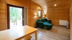 Un intérieur de chalet chaleureux avec des murs en bois, un canapé, une table et une vue sur l’extérieur.