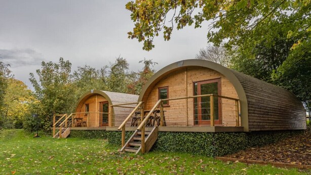 Deux cabanes en bois en forme de dôme, dotées d’une terrasse en bois et d’un escalier menant à l’entrée.