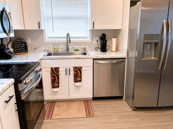 Una cocina compacta equipada con estufa, lavaplatos, fregadero y refrigerador.