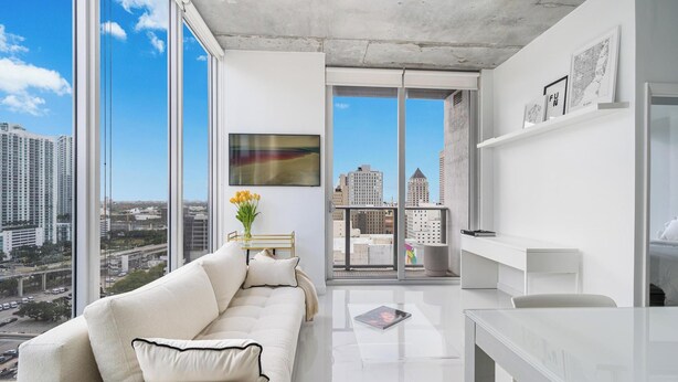 A modern apartment with a large balcony, a white sofa, a glass table, and a city view. - 2bed2 bath apartment. FREE PARKING, POOL&GYM (Miami)