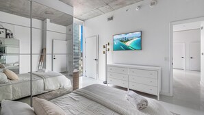A modern bedroom with a large bed, a dresser, and a television mounted on the wall. - 2bed2 bath apartment. FREE PARKING, POOL&GYM (Miami)