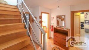Una escalera que conduce a un segundo piso, un aparador de madera, un espejo y un extintor.