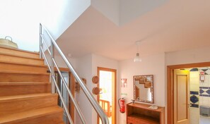 A staircase leading to a second floor, a wooden dresser, a mirror, and a fire extinguisher. - Casa da Cestaria T2 Duplex by YHA (Cabanas de Tavira)