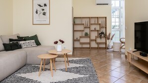 Een woonkamer met een bank, een salontafel, een televisie en een boekenkast.