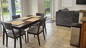 Un vaste espace de vie comprenant une table à manger, des chaises, un canapé et un téléviseur fixé au mur.