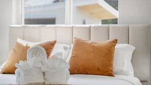 A neatly made bed with white and brown pillows, a rolled white towel, and a brown blanket. - Beach Family Tiki Villa Walk to Beach Heated Pool (Pompano Beach)