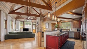 A spacious living area with a wooden ceiling, a built-in kitchen with granite countertops, and a stone accent wall. - Alpine 28: Luxe Keystone Mountain Home - Sleeps 16 (Dillon)