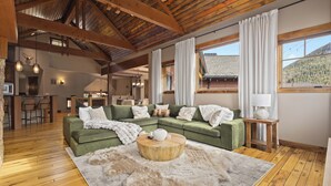 A spacious living room with a green sectional sofa, a wooden coffee table, and a large fur rug. - Alpine 28: Luxe Keystone Mountain Home - Sleeps 16 (Dillon)