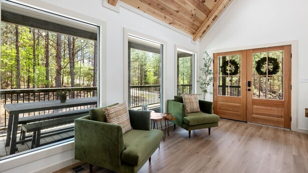 A spacious room with large windows, a wooden ceiling, and a green sofa.