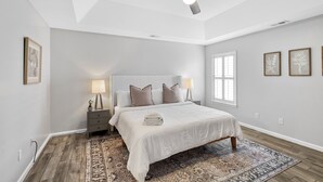 A bedroom with a bed, bedside lamps, a ceiling fan, and a patterned rug.