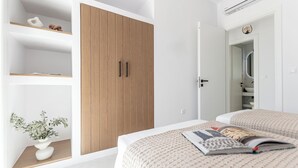 Una camera da letto moderna con un'armadio in legno, un comodino con una pianta e un letto con una rivista.