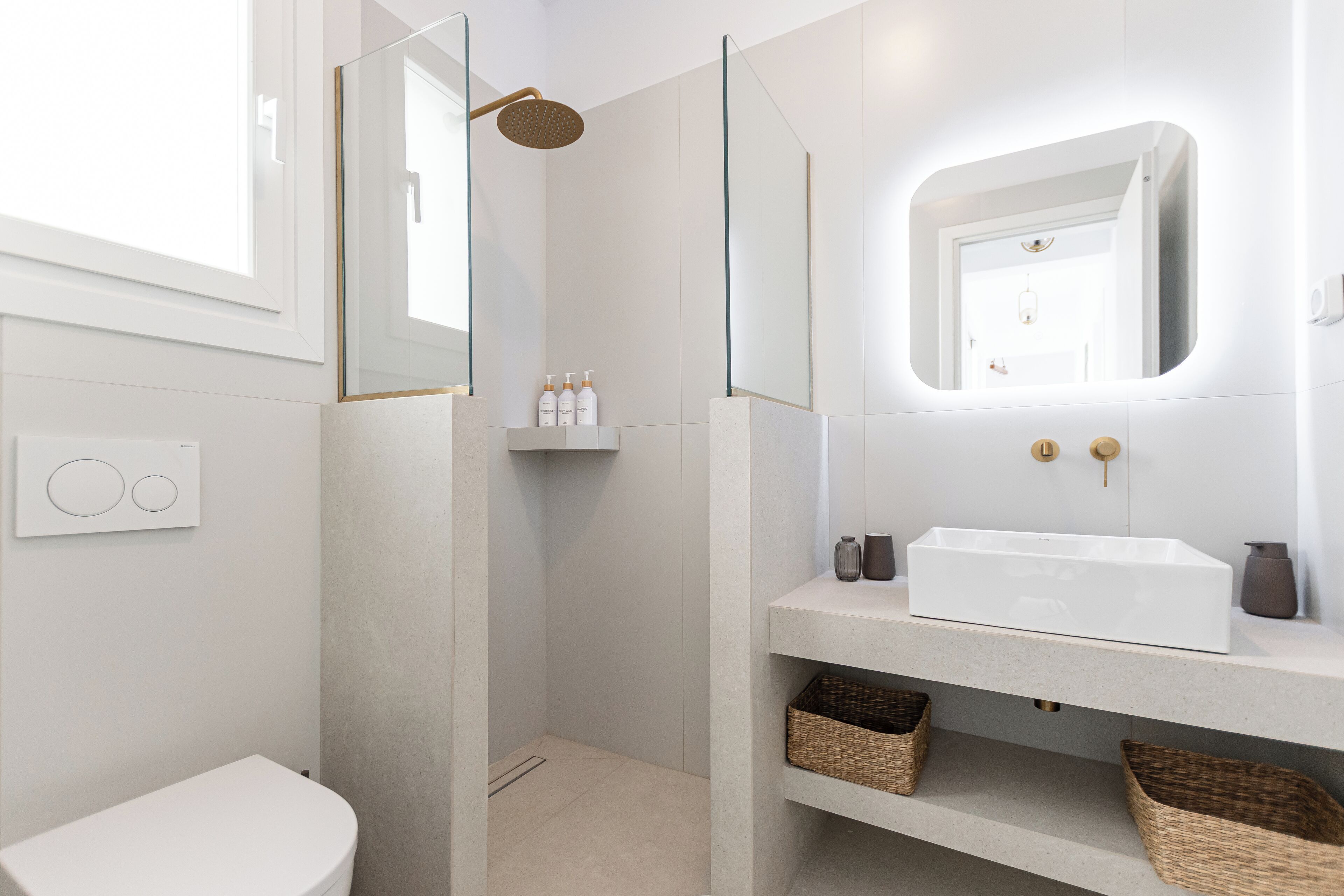 A modern bathroom with a white sink, a glass shower enclosure, and a mirror above the sink.