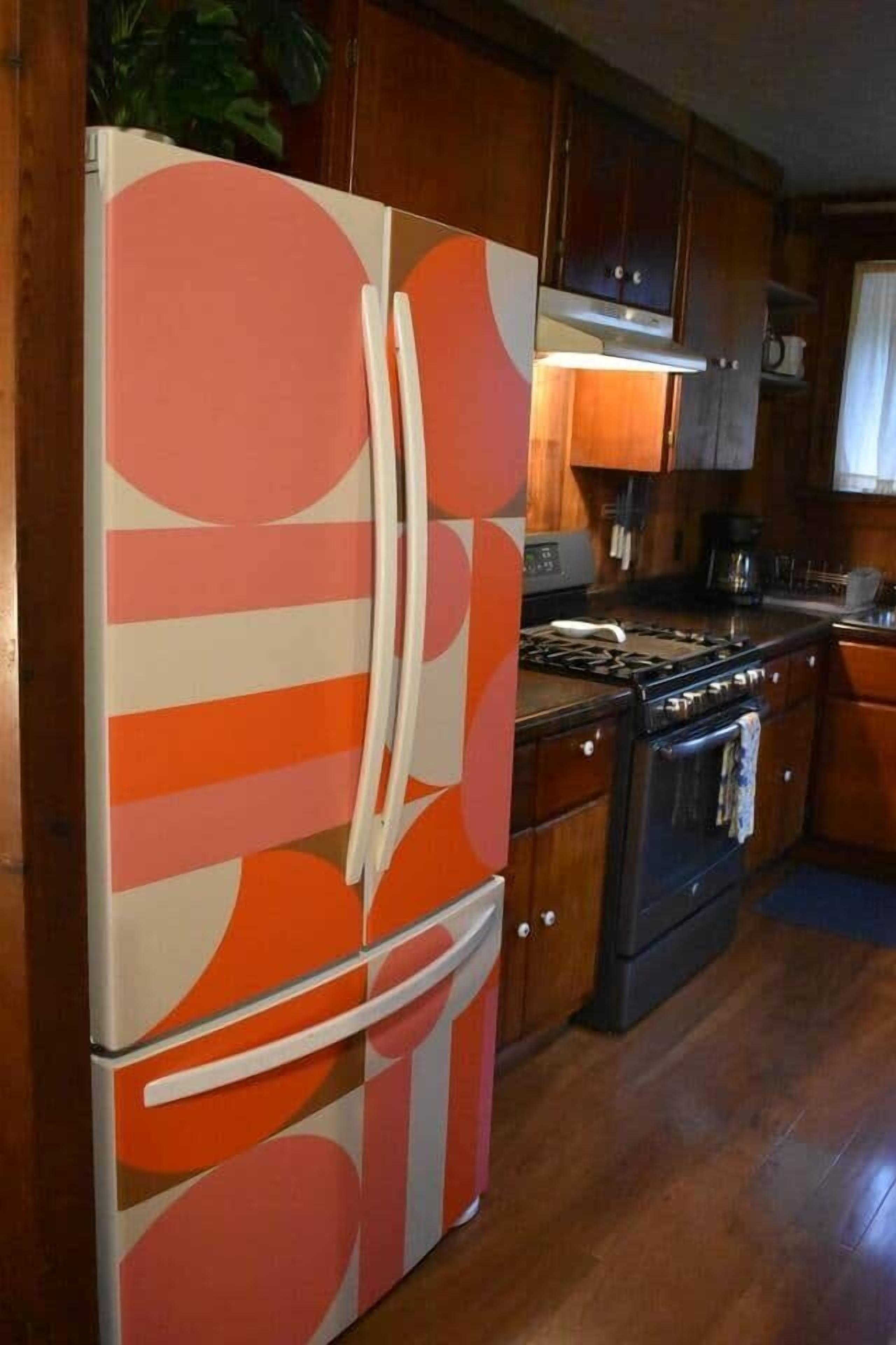 Une cuisine avec des meubles de rangement en bois, un réfrigérateur orné d’un motif géométrique, une cuisinière et un évier.